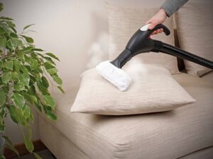 A hand using a steam cleaner on a sofa cushion, a service provided by Nashville Carpet Cleaning in Madison, TN.