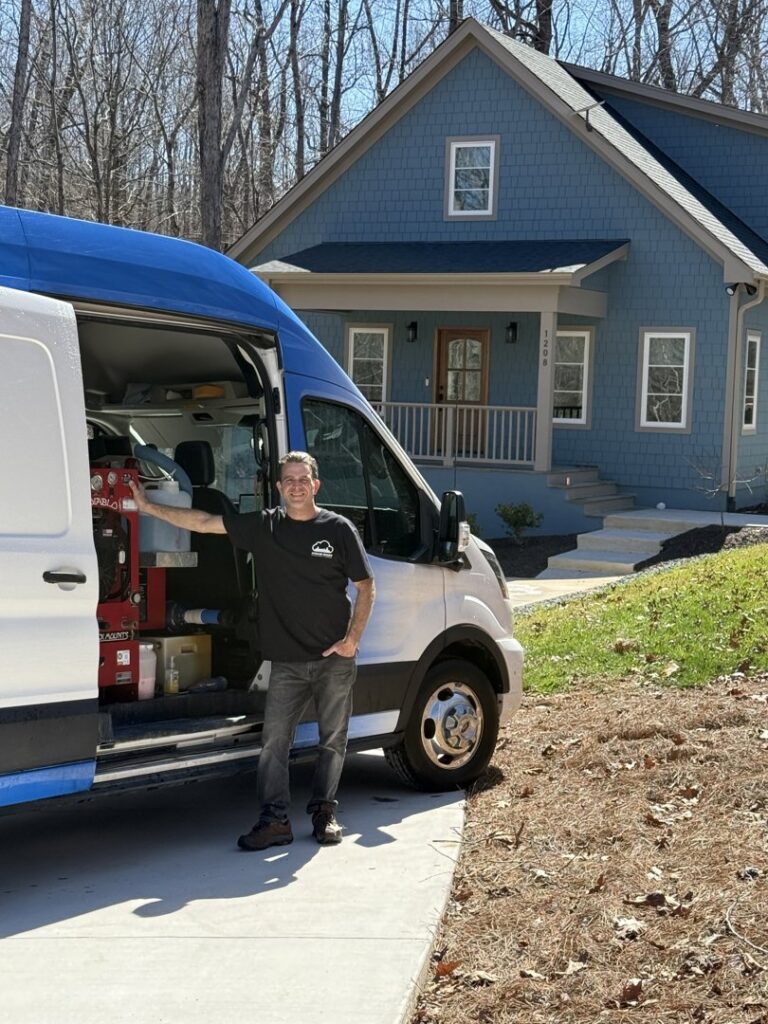 A Steam Giant technician standing proudly next to the branded service van at a job site in Raleigh, NC.