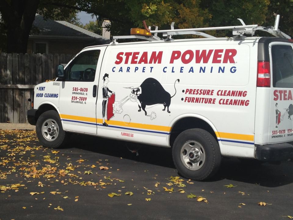 Steam Power Carpet Cleaning service van parked outside, displaying business name and services in Springfield, IL.