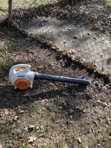 A Stihl leaf blower resting on the ground amidst leaves, ready for use by A&B Lawn Services in Baytown, TX.