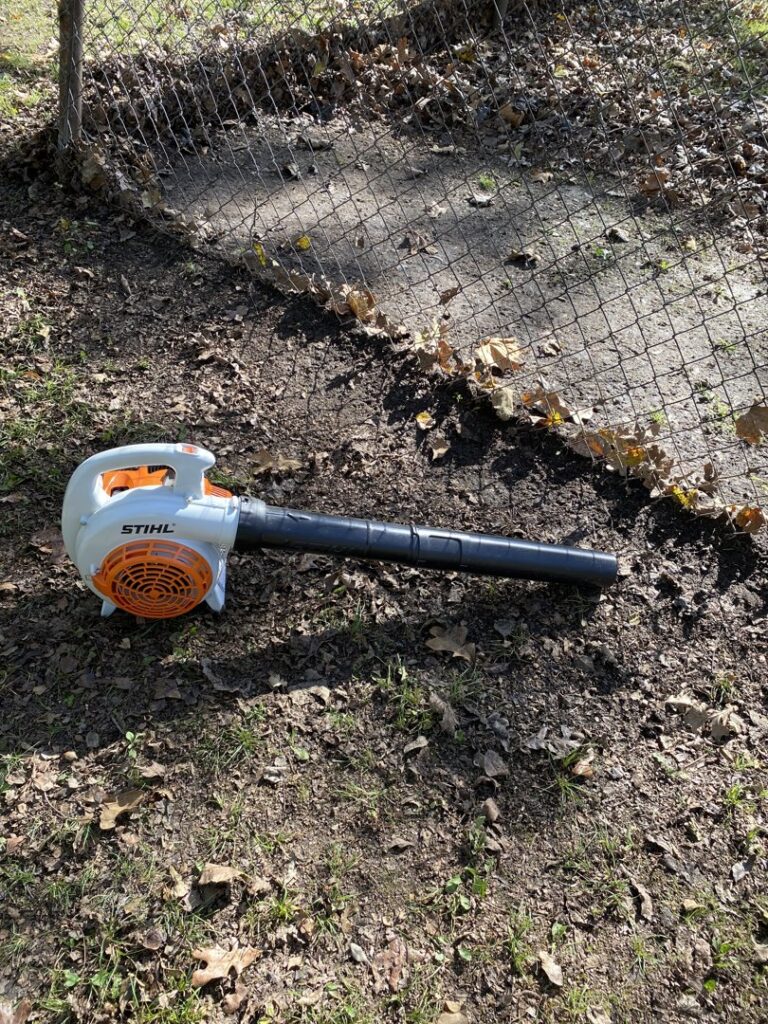 A Stihl leaf blower resting on the ground amidst leaves, ready for use by A&B Lawn Services in Baytown, TX.