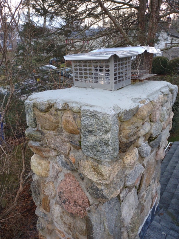 A newly installed chimney cap on a stone chimney, showcasing quality work by Elite Home Solutions in Warwick, RI.
