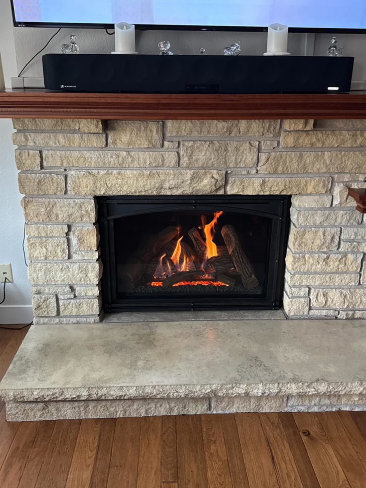 A beautiful stone fireplace with a gas insert and active flames installed by Spartan Heating, Cooling and Fireplaces in Cedar Rapids, IA
