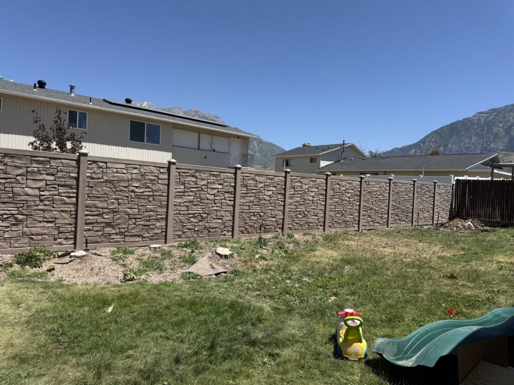A durable stone-texture privacy fence installed in a residential backyard by Stonehenge Fence & Deck in Orem, UT.