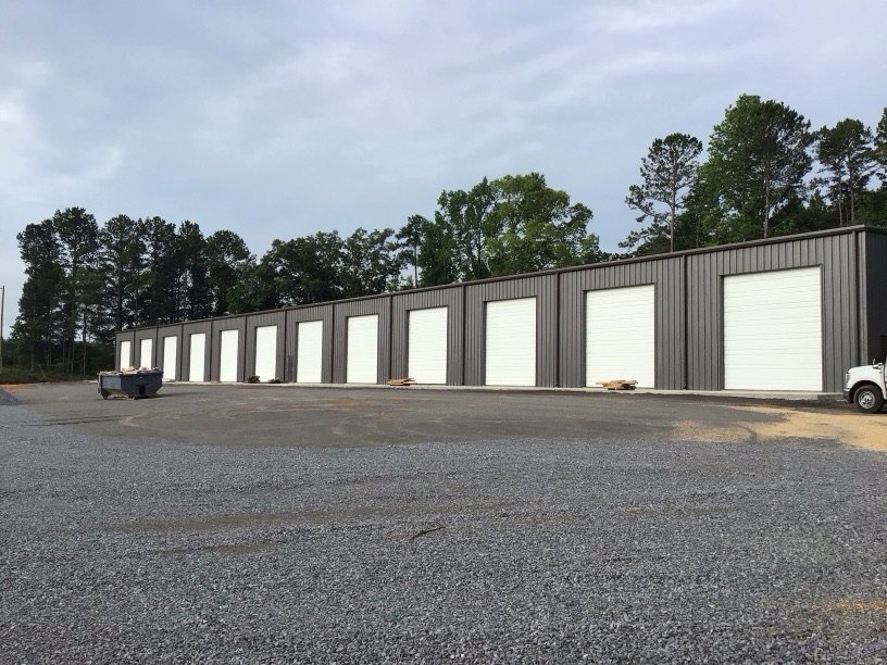 A row of storage units with newly installed white roll-up garage doors by Magic City Door Huntsville in Birmingham, AL.
