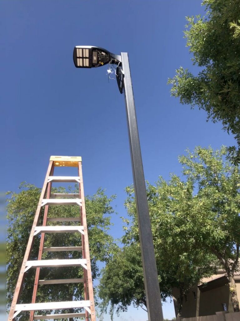 Electrician ladder next to a street light pole, indicating installation or repair by EV Electric LLC in Mesa, AZ