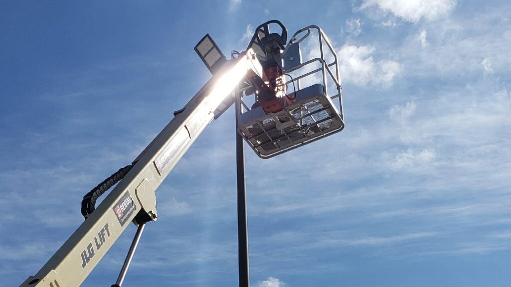 A JLG lift bucket extended towards a street light pole for maintenance by Big City Lighting and Electric in Houston, TX.