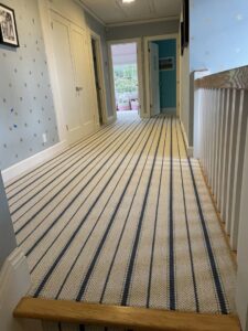 A long hallway with striped carpet leading to stairs, expertly installed by Straus Carpets in Oakland, CA.
