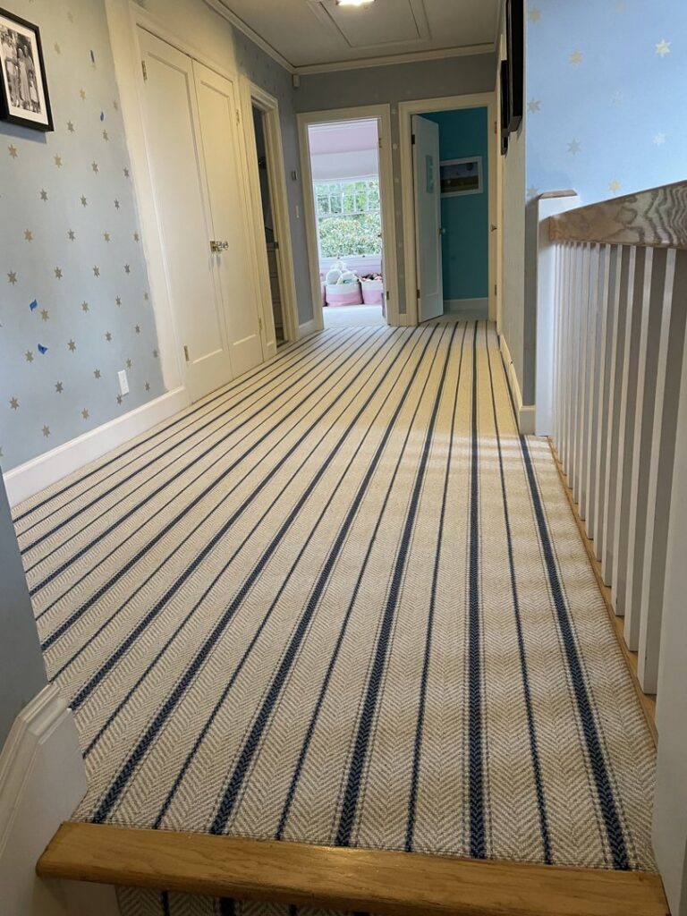 A long hallway with striped carpet leading to stairs, expertly installed by Straus Carpets in Oakland, CA.