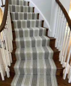 A beautifully installed striped carpet stair runner on wooden stairs by AguirreFloorz in Colorado Springs, CO.