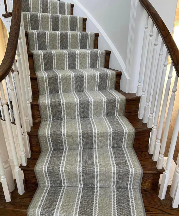 A beautifully installed striped carpet stair runner on wooden stairs by AguirreFloorz in Colorado Springs, CO.
