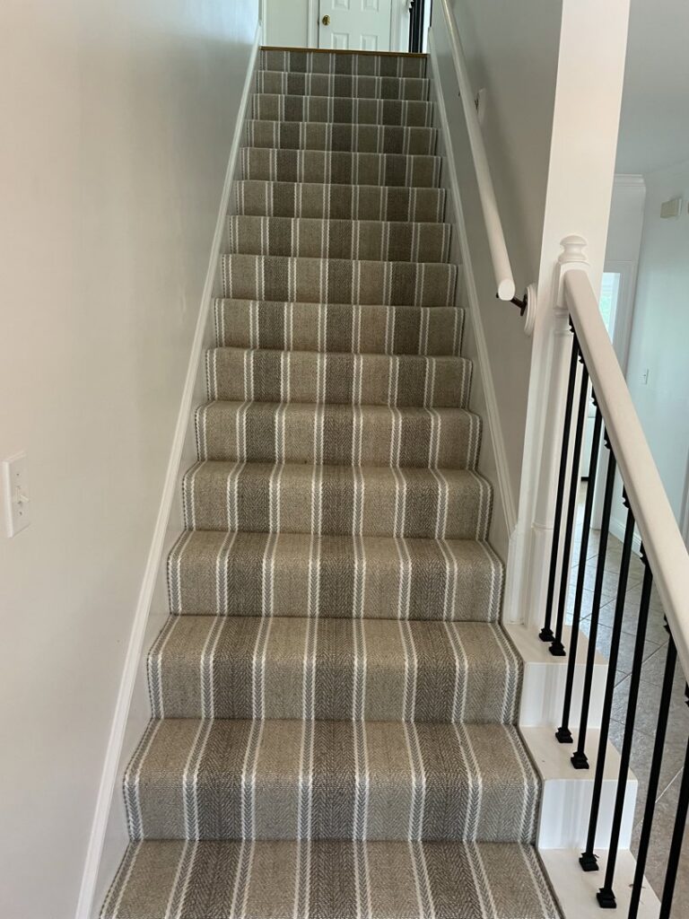 A newly installed striped carpet stair runner, demonstrating a carpet contractor job by Flooring Dunn Right in Biloxi, MS