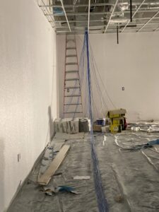 A room under construction with blue structured data cables hanging from the ceiling, showing an installation in progress by CAAM Integration LLC in Albuquerque, NM.