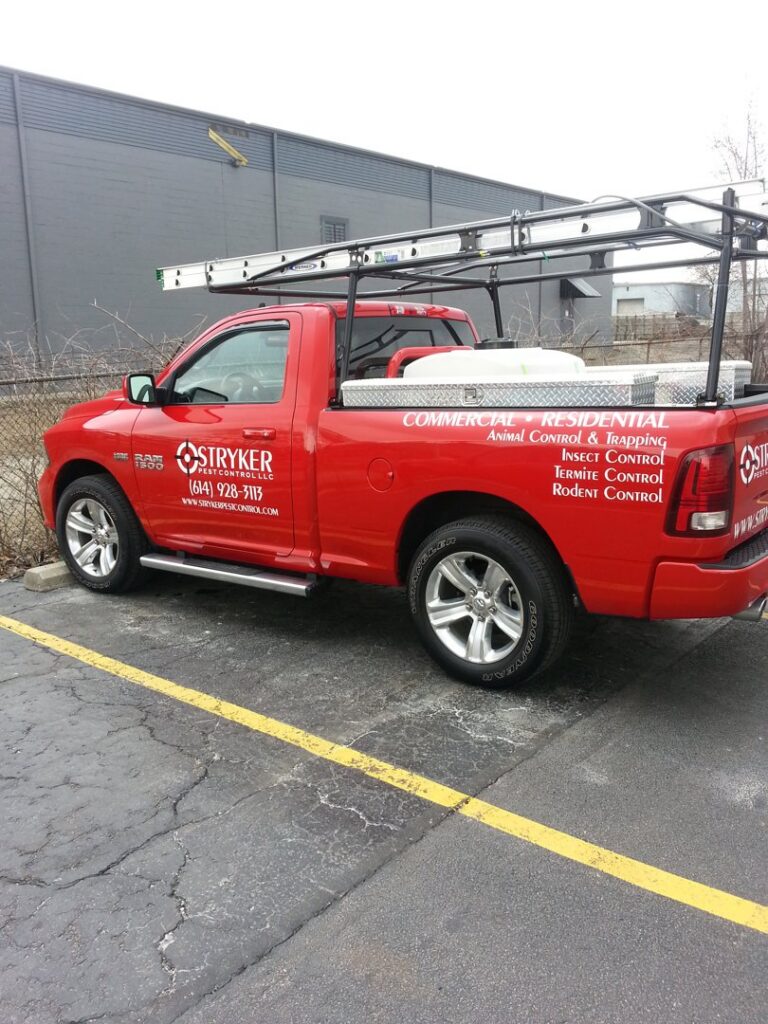 A red Stryker Pest Control LLC service truck with ladders and equipment parked in Columbus, OH.