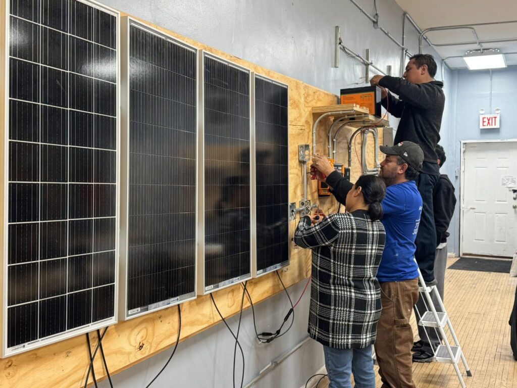 Students installing and wiring solar panels on a training board at Escuela Tecnica ABC in North Chicago, IL
