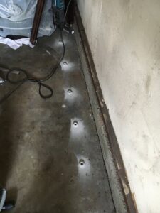 Drilled holes in a concrete floor for sub-slab termite treatment by Intensive Pest Control in Long Beach, CA.