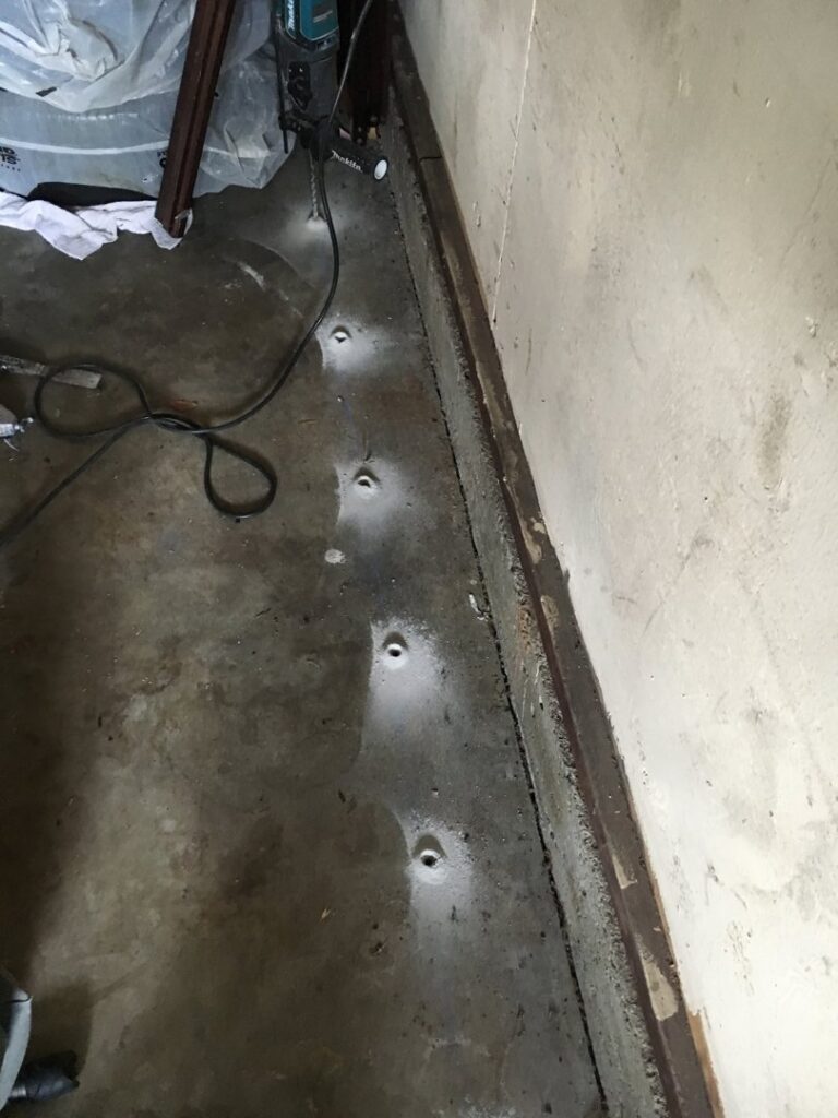 Drilled holes in a concrete floor for sub-slab termite treatment by Intensive Pest Control in Long Beach, CA.