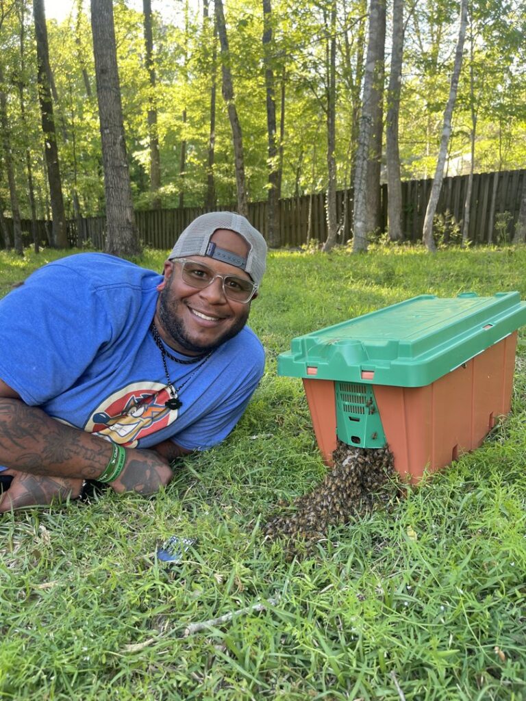 A technician smiling next to a bee box with bees, after a successful relocation by A&E Bee Extraction and Control in Mount Pleasant, SC.