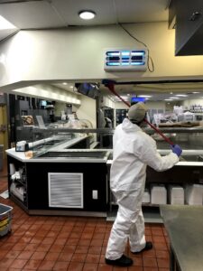 A Sunbuzz Pest Control & Environmental Services technician in a hazmat suit performing commercial pest control near a fly trap in Fort Lauderdale, FL.