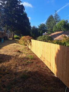 A long wooden privacy fence installed in a sunny backyard by Fix-A-Fence LLC in Portland, OR.