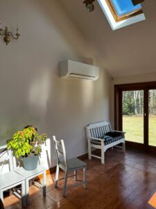 A ductless mini-split heat pump unit installed on a wall in a bright sunroom or living area by A&D Ductless LLC in Lunenburg, MA.