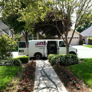 A Superior Carpet Care van with cleaning hoses extended into a home for service in Fresno, CA.