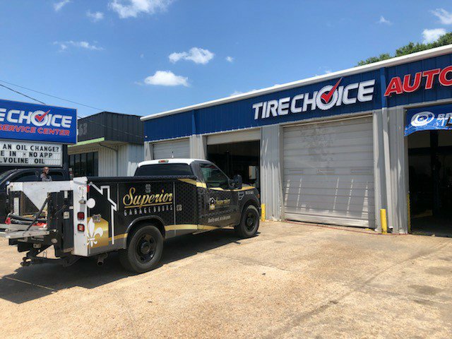 A Superior Garage Door & Repairs branded truck parked at a commercial job site, a Tire Choice Auto Service Center, in Lafayette, LA.