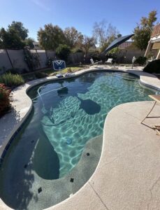 A swimming pool with a cleaning hose in the water, indicating service by Pool Pals in Franklin, MA.