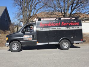 A Symbiont Services branded service van with a technician, ready for HVAC jobs in Englewood, FL.