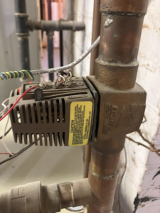 A close-up of a Taco valve on copper pipes, part of a heating system serviced by AVS Heating and Air Conditioning in Alexandria, VA.