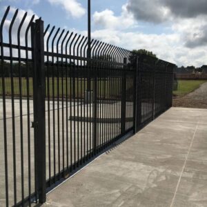 A tall black security fence with a sliding gate and pointed tops, installed by Texas Fence and Iron Co. in Houston, TX.