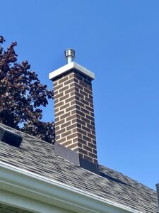 A tall, newly repaired brick chimney with a shiny new cap by JJ Chimney Services in Minneapolis, MN.