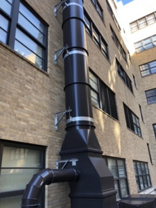 A tall HVAC vertical exhaust stack installed on the side of a building by Kuhlmann Supply Company in Earth City, MO