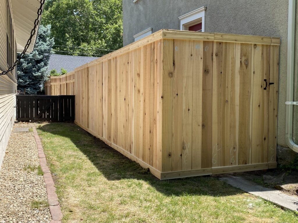 A long, tall natural wood privacy fence installed alongside a house by ZBros Fencing LLC in Boise, ID.