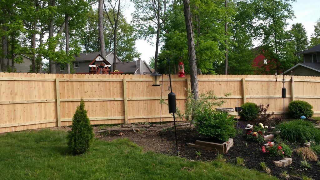 A tall wooden privacy fence installed in a residential backyard by Sharper Image Fence in Fort Wayne, IN.