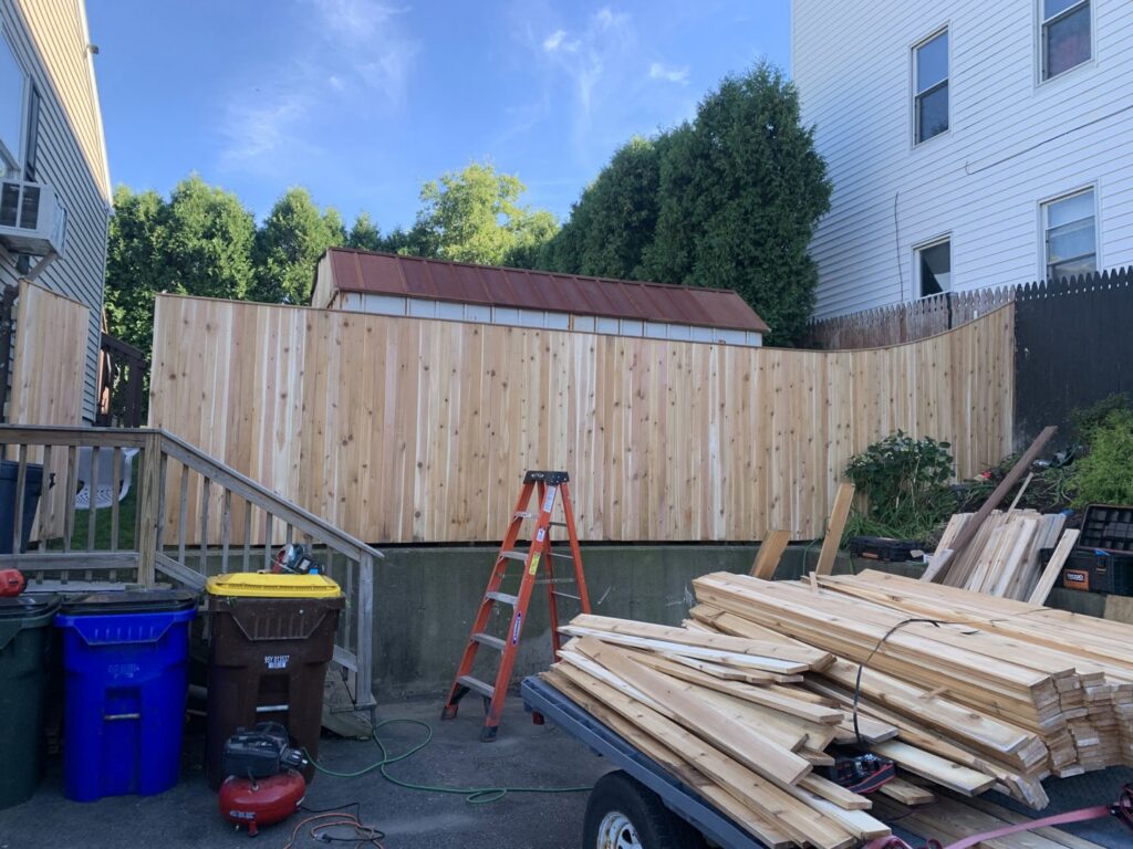 Tall wood privacy fence under construction with materials on site by Louis Fence installations & repairs in Fall River, MA