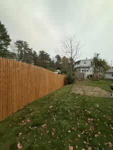 A tall wooden picket fence providing privacy for a residential backyard, installed by Triple P Fence in Augusta, ME.