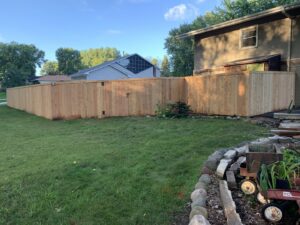 A tall wooden privacy fence with a gate providing security for a backyard by Top Notch Fence in East Bethel, MN