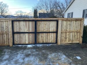 A tall wooden privacy fence with a sturdy double gate installed by Doolan Fence in Montpelier, VT.