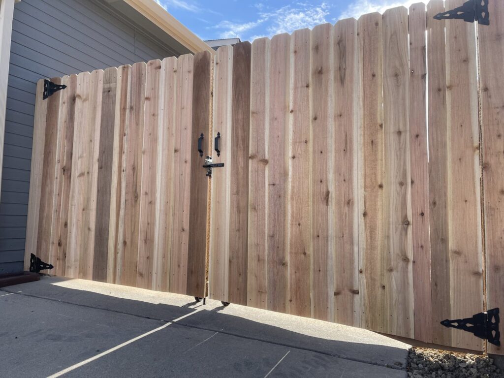 A newly installed tall wooden privacy fence with a double gate, completed by North CO Fence & Deck in Greeley, CO.