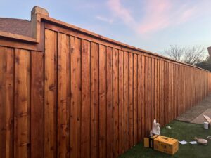 A tall, newly installed wooden privacy fence next to a residential property, built by QD & E Fencing in Fort Worth, TX.