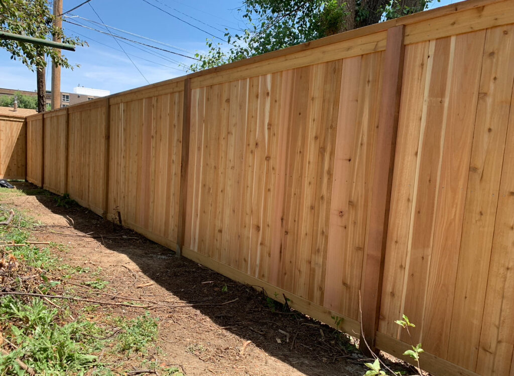A newly installed tall wooden privacy fence in a residential area by Colorado Springs Fence Company in Colorado Springs, CO.