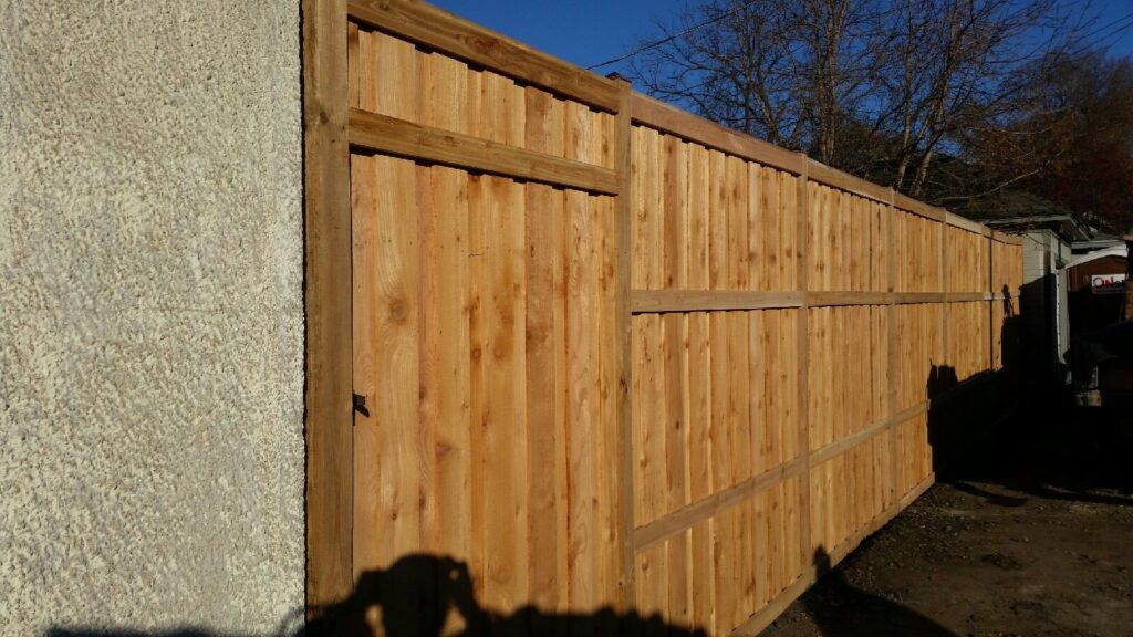 A tall wooden privacy fence with a gate, providing security and seclusion, installed by Mauer Company in Little Canada, MN.