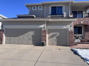 Residential property featuring two tan panel garage doors, expertly installed by Pham Garage Door Service & Repair in Arvada, CO.