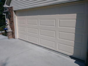 A tan panel residential garage door installed on a home by R&A Overhead Door in Gower, MO.