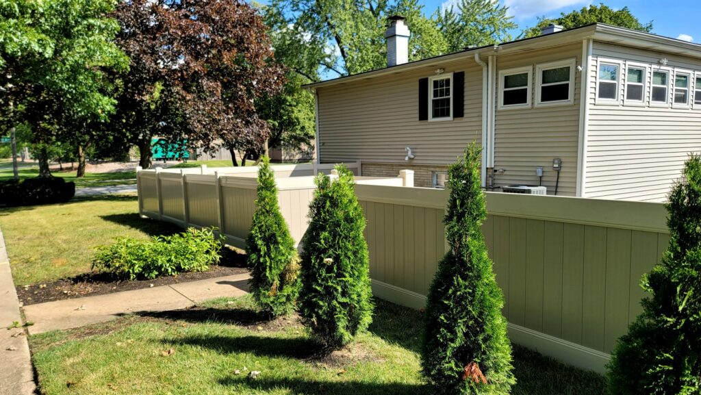 A tan vinyl privacy fence installed along a residential sidewalk by AmeriDream Fence & Deck in Joliet, IL.