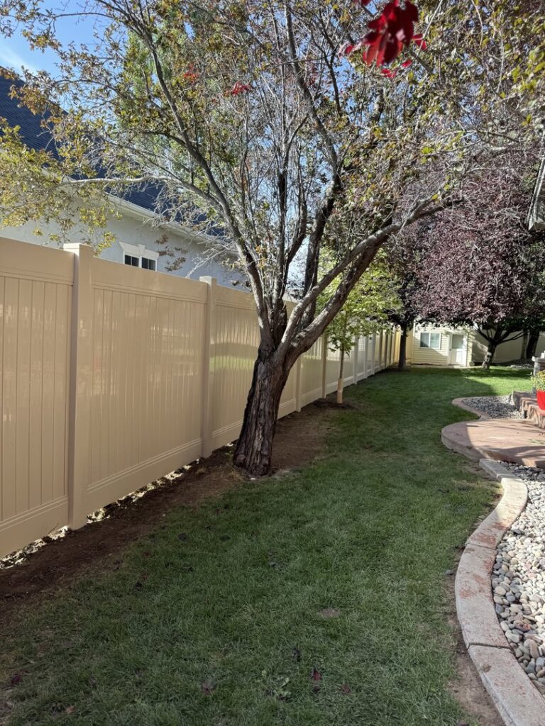A tan vinyl privacy fence installed in a residential backyard by 208 Fence and Gate in Idaho Falls, ID.
