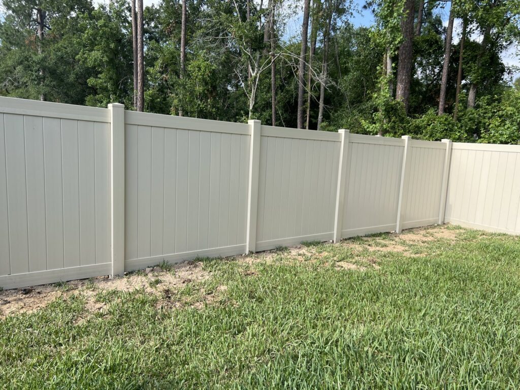 A newly installed tan vinyl privacy fence in a residential backyard by R&R Fence Services in Jacksonville, FL.