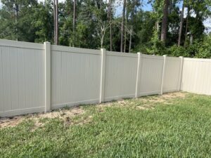 A newly installed tan vinyl privacy fence in a residential backyard by R&R Fence Services in Jacksonville, FL.