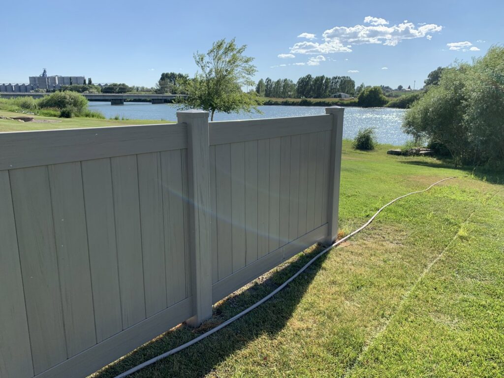 A tan vinyl privacy fence installed along a waterfront property by Idaho Falls Fencing in Idaho Falls, ID.